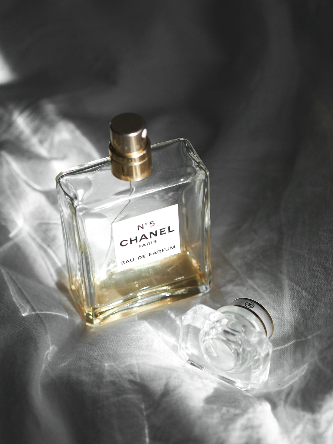 clear glass perfume bottle on white textile