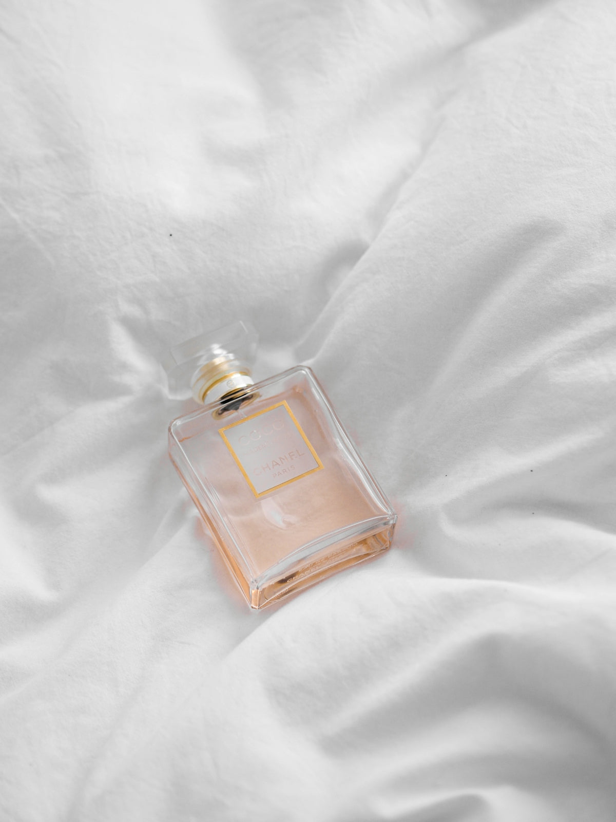 clear glass perfume bottle on white textile