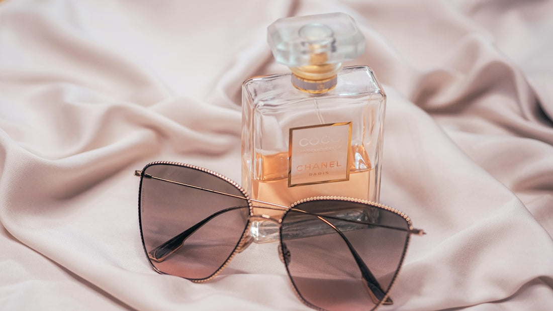 black framed sunglasses beside perfume bottle