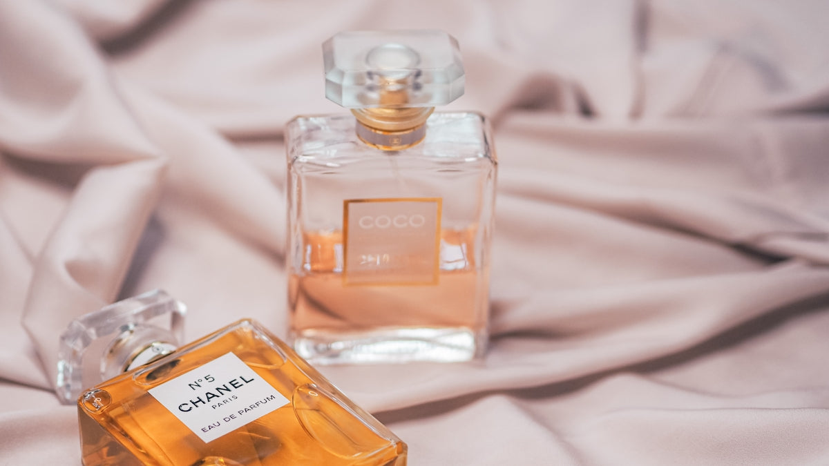 clear glass perfume bottle on white textile