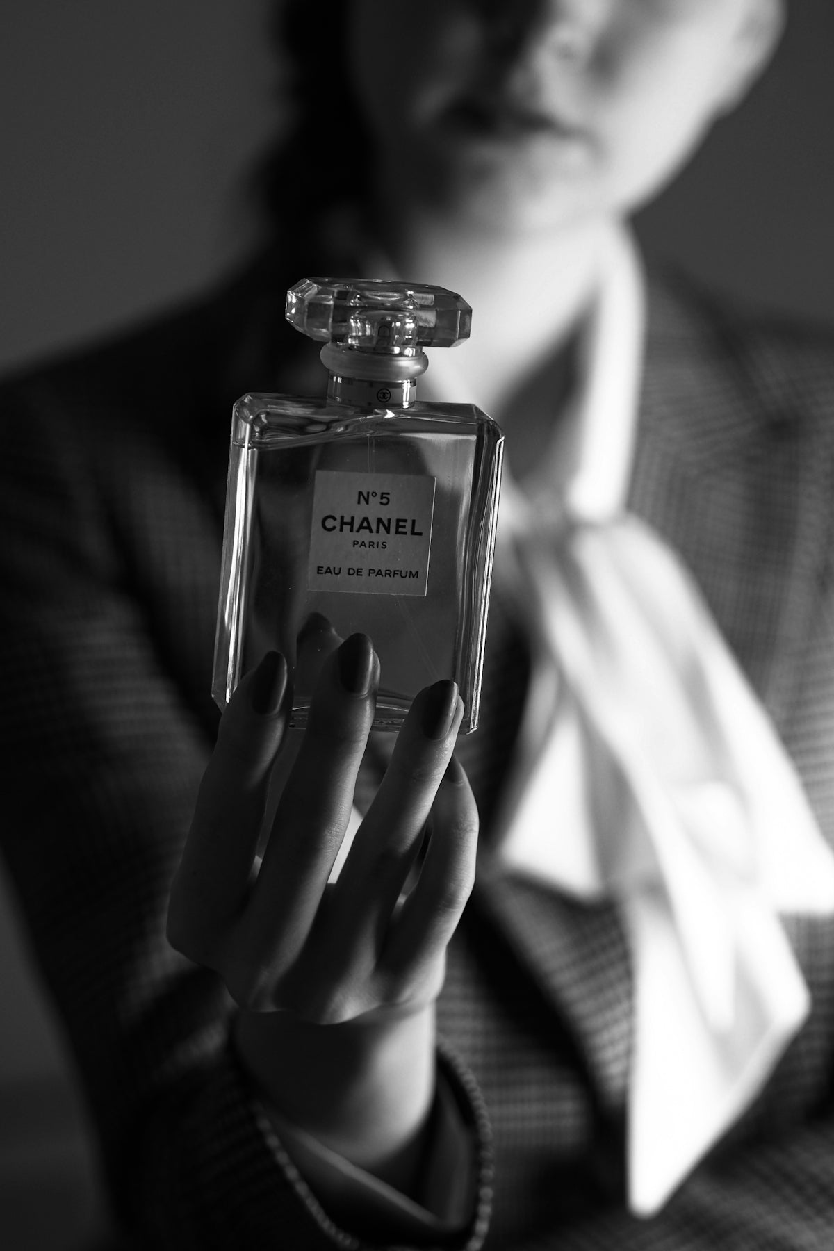 a woman in a suit holding a bottle of chanel