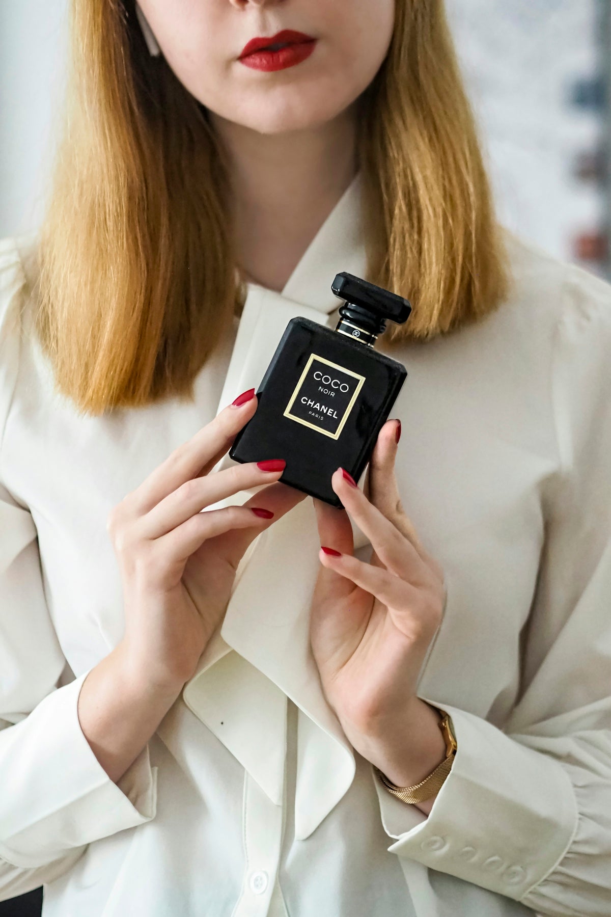 A woman holding a bottle of perfume in her hands
