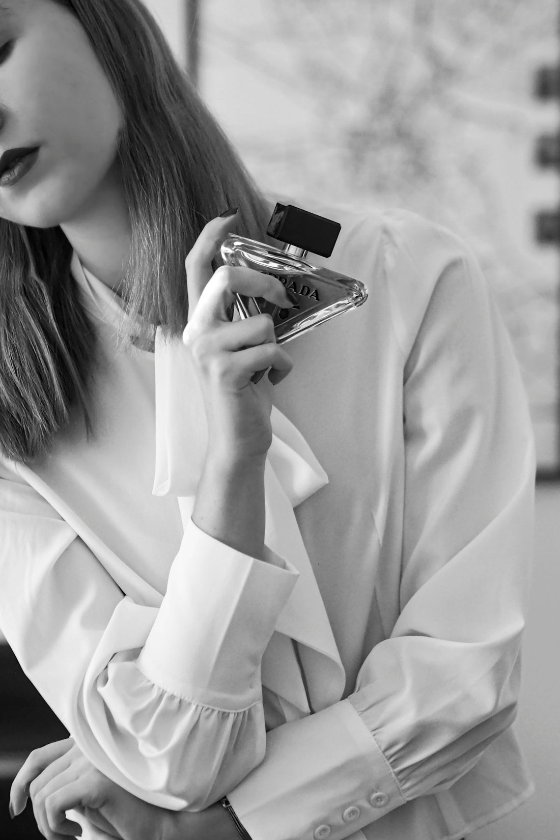 A woman holding a bottle of perfume in her hand
