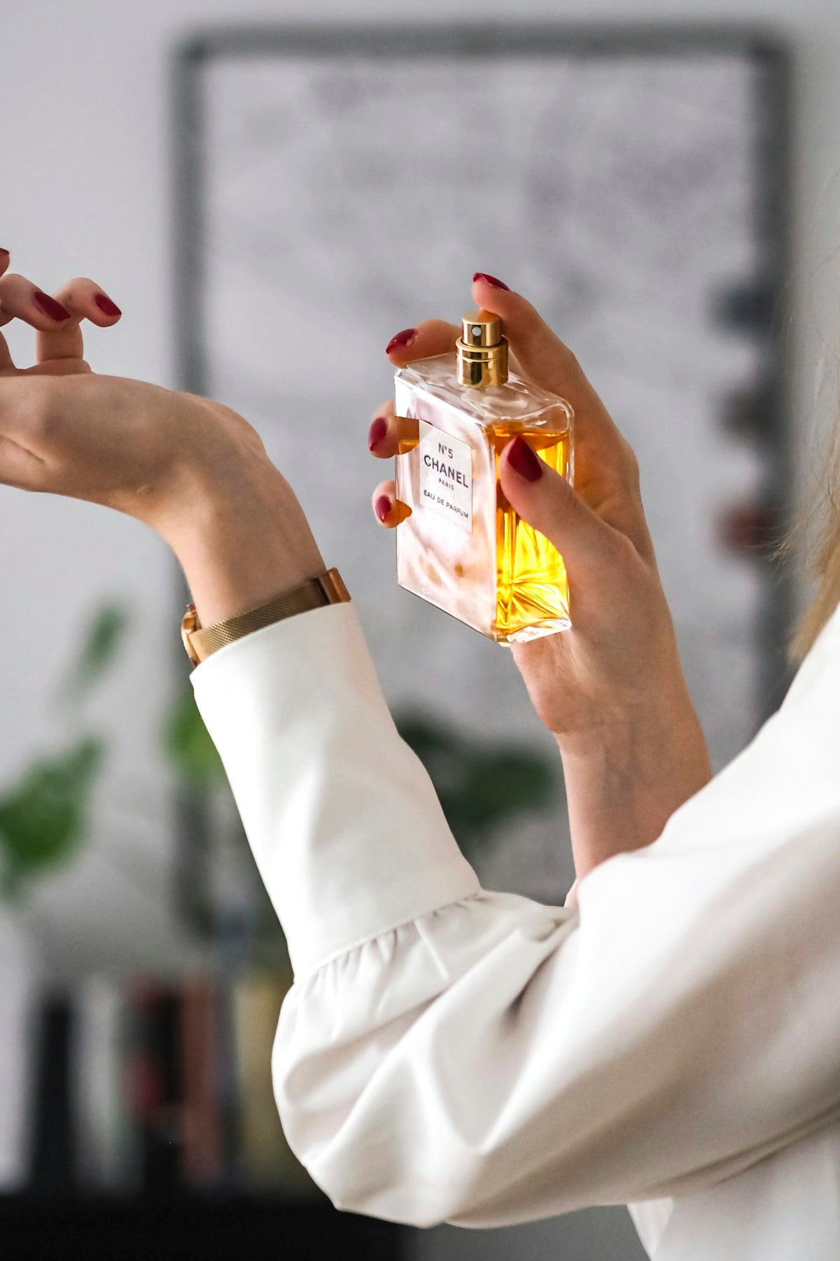 A woman holding a bottle of perfume in her hand