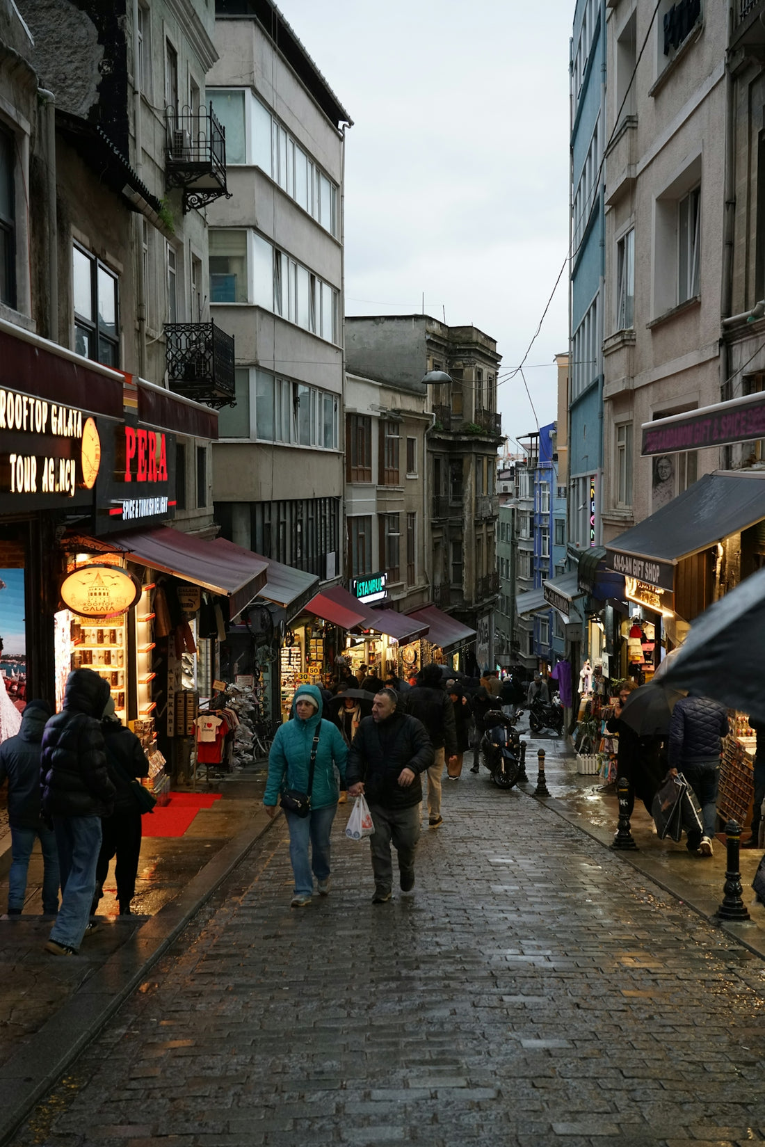 A group of people walking down a street next to tall buildings