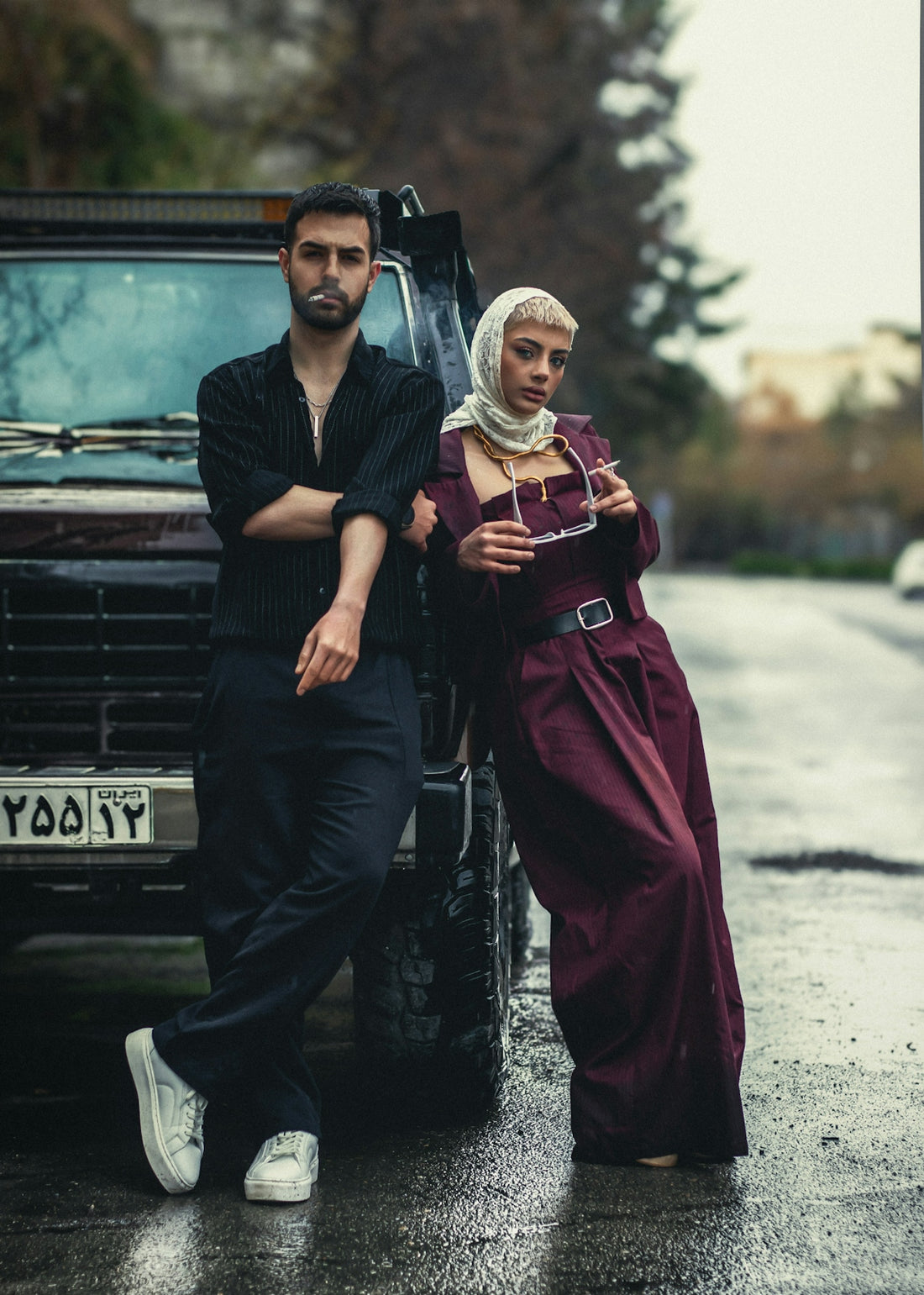 A man and a woman pose by a vehicle.