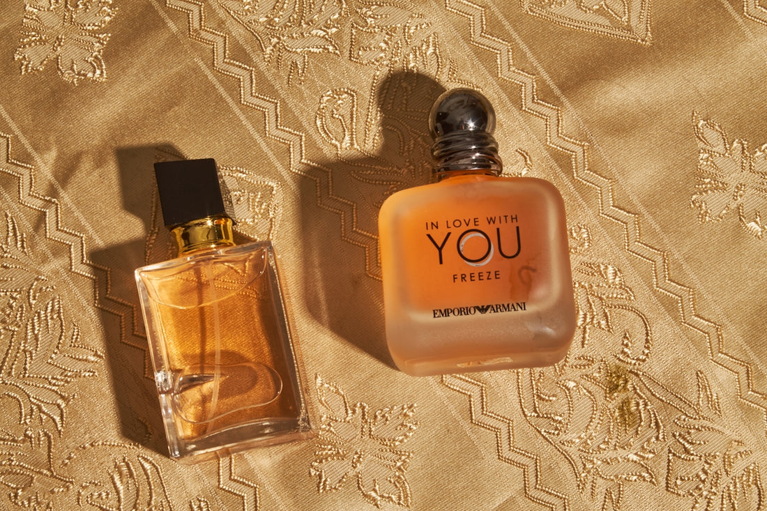 Two perfume bottles on a golden patterned fabric.