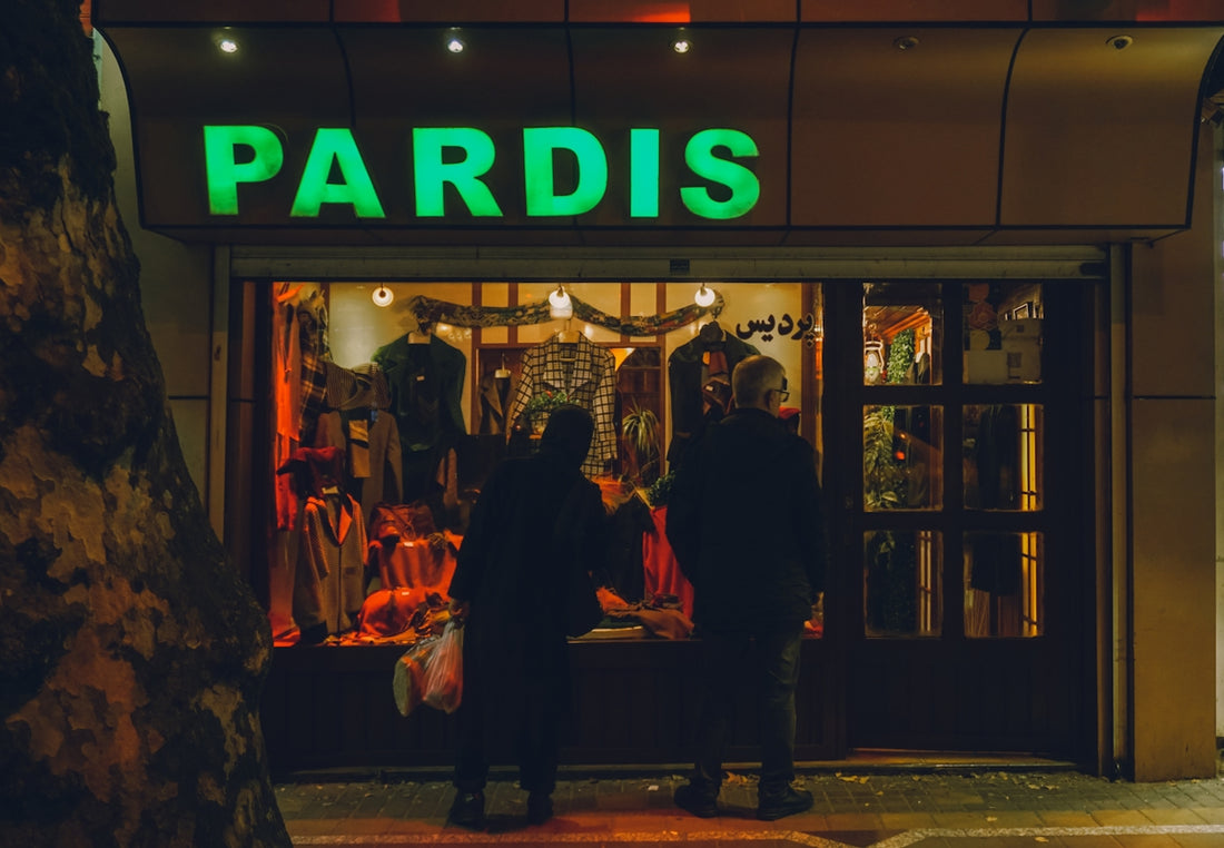 Two people looking into a store window at night.