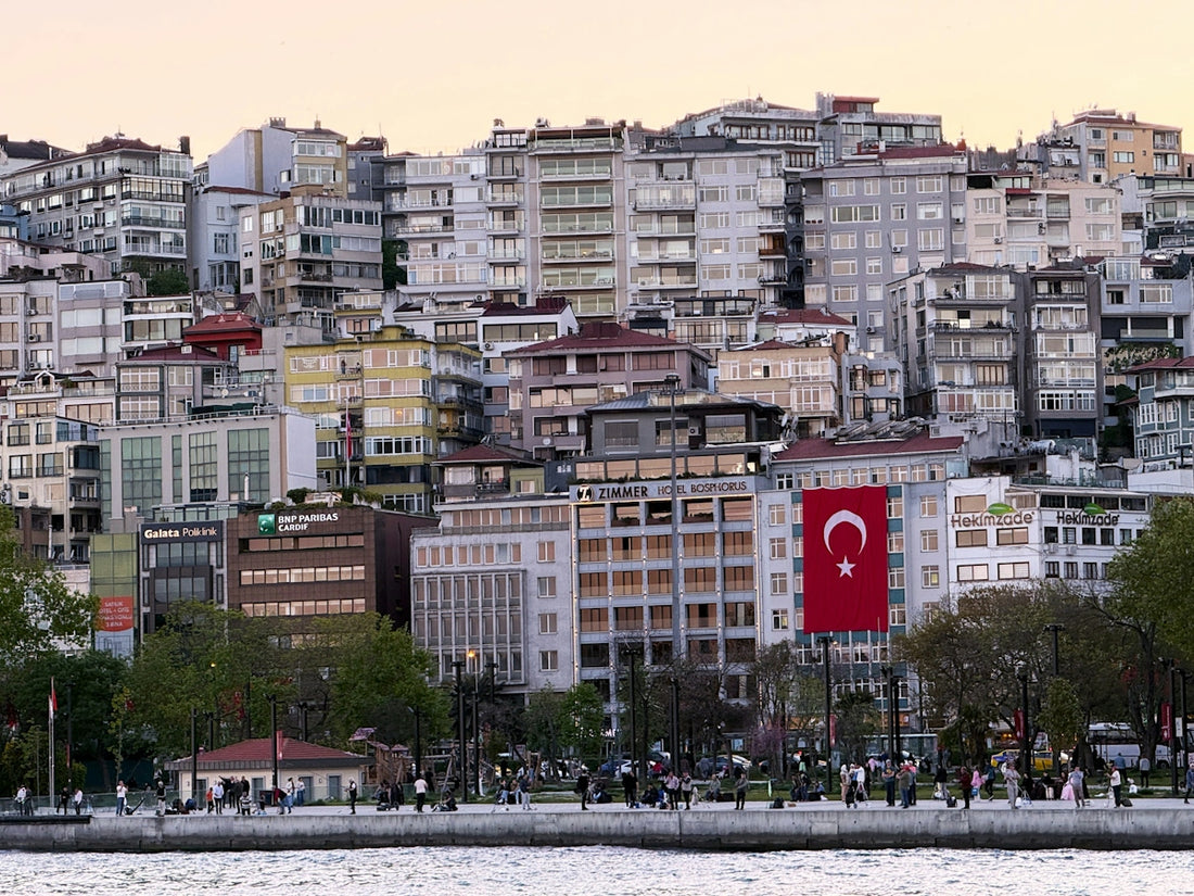 Dense cityscape with a large turkish flag overlooking a waterfront.